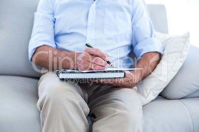 Businessman writing while sitting on sofa