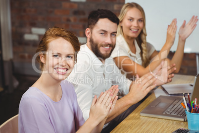 Portrait of happy colleagues clapping at meeting
