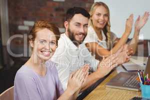 Portrait of happy colleagues clapping at meeting