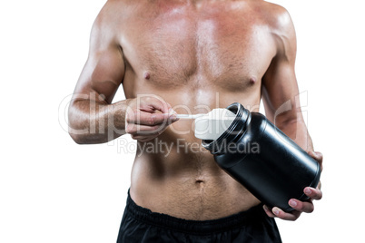 Midsection of shirtless man scooping up protein powder