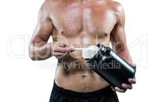 Midsection of shirtless man scooping up protein powder