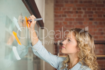 Creative businesswoman writing on sticky notes in office