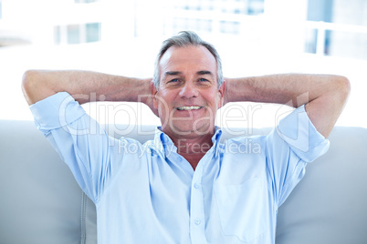 Happy man sitting with hands in hair at home