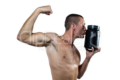 Athlete flexing muscles while kissing nutritional supplement con