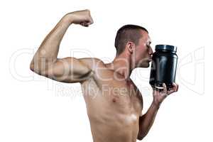 Athlete flexing muscles while kissing nutritional supplement con