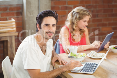 Portrait of businessman using laptop with colleague in backgroun