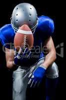 Upset American football player kneeling while holding ball