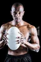 Portrait of confident shirtless sportsman holding rugby ball
