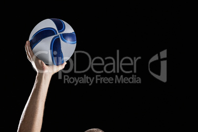 Rugby player with arm raised holding ball