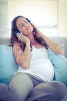 Pregnant woman listening music at home