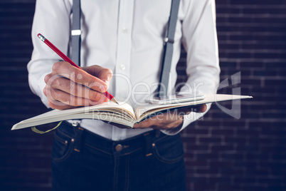 Midsection of businessman using cellphone while writing