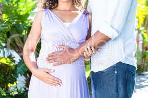 Midsection of pregnant wife with husband touching belly