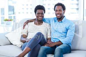 Happy man with pregnant wife sitting at home