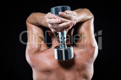Rear view of shirtless sports player working out with dumbbell