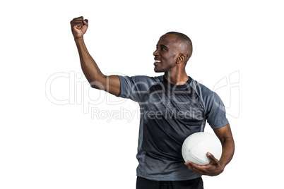Sportsman with clenched fist holding rugby ball after victory