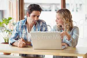 Business people looking at laptop while sitting in office