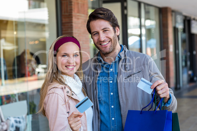 Smiling couple with shopping bags showing credit card Smiling couple with shopping bags showing credit card
