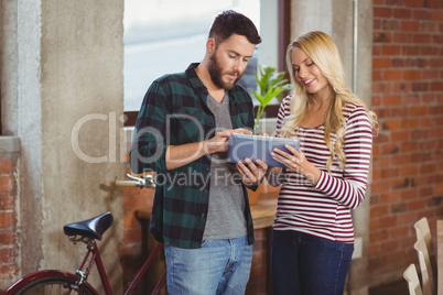 Cheerful businesswoman with colleague using digital tablet