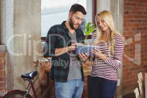 Cheerful businesswoman with colleague using digital tablet