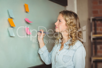 Confident businesswoman holding marker by board