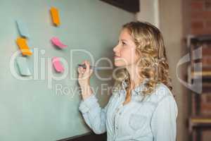 Confident businesswoman holding marker by board