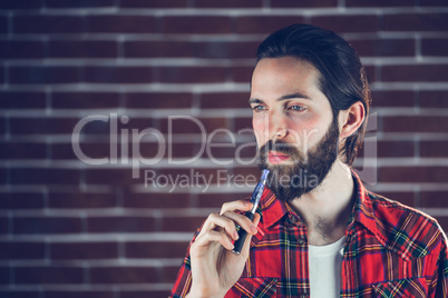 Thoughtful hipster holding electronic cigarette