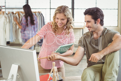 Man and woman pointing towards computer in office