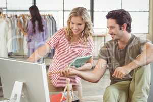 Man and woman pointing towards computer in office