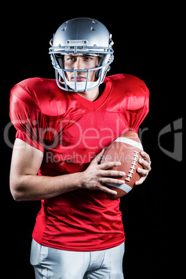 Confident American football player holding ball