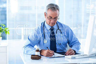 Male doctor writing prescription in hospital