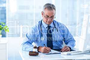 Male doctor writing prescription in hospital
