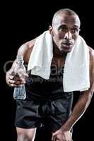 Tired athlete holding water bottle while hand on knee