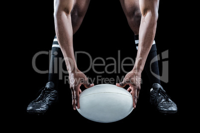 Low section of sportsman holding ball while playing rugby