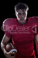 Serious American football player holding ball