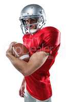 Portrait of confident American football player in red jersey hol