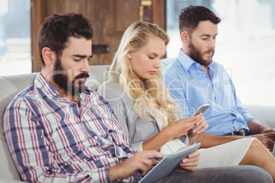 Business people using technologies while sitting on sofa