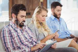 Business people using technologies while sitting on sofa