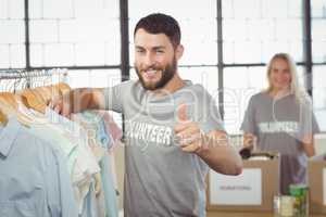 Portrait of happy man gesturing thumbs up while selecting clothe