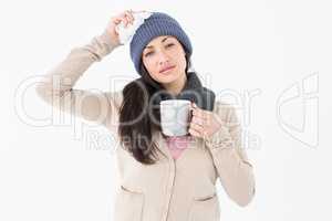 Sick brunette holding a mug and looking at the camera