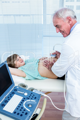 Doctor holding equipment on belly of pregnant woman