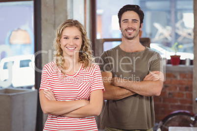 Portrait of man and woman with arms crossed in office