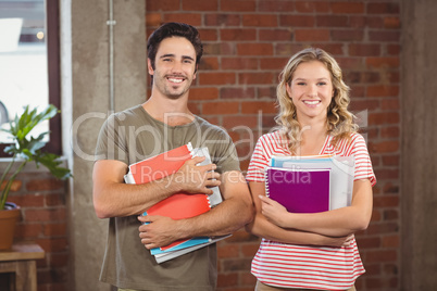 Portrait of business people holding files and folders in office