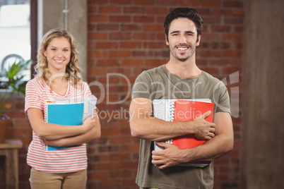 Portrait of smiling businessman holding files and folders in off