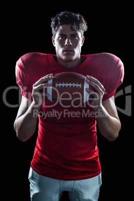 Portrait of determined American football player with ball standi