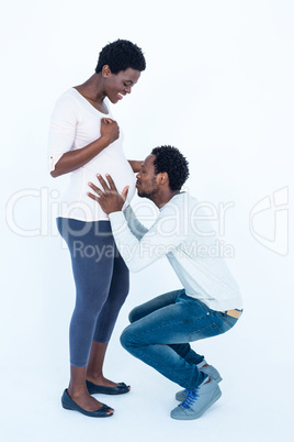 Affectionate man kissing belly of his wife