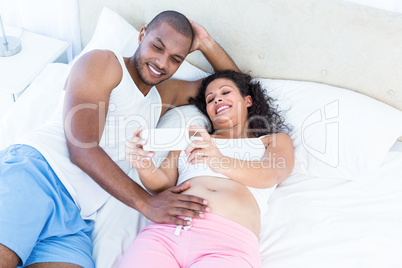 Pregnant wife showing smartphone to husband