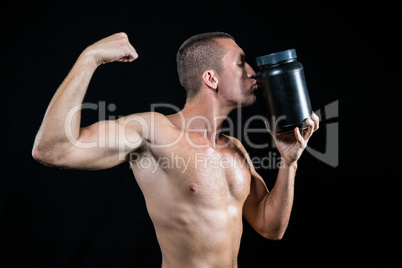 Athlete flexing muscles while kissing container
