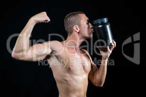Athlete flexing muscles while kissing container
