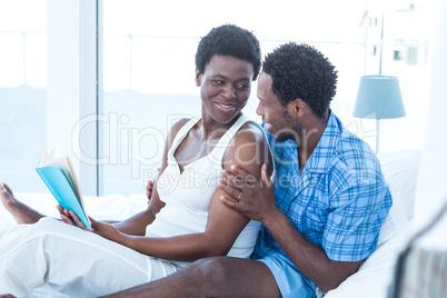 Wife looking at husband while holding book