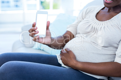 Mid section of pregnant woman showing mobile phone